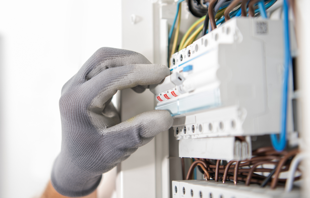 Electrician Wearing Safety Gloves Testing Fuses Inside an Apartment Located Electric Box.